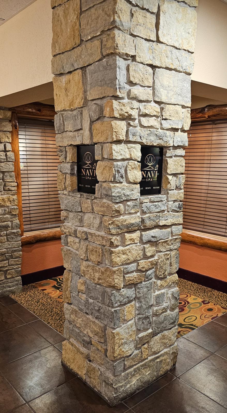 Photo of a stone pillar at the front of the Navi Spa entrance, featuring plaques with Navi Spa logo.