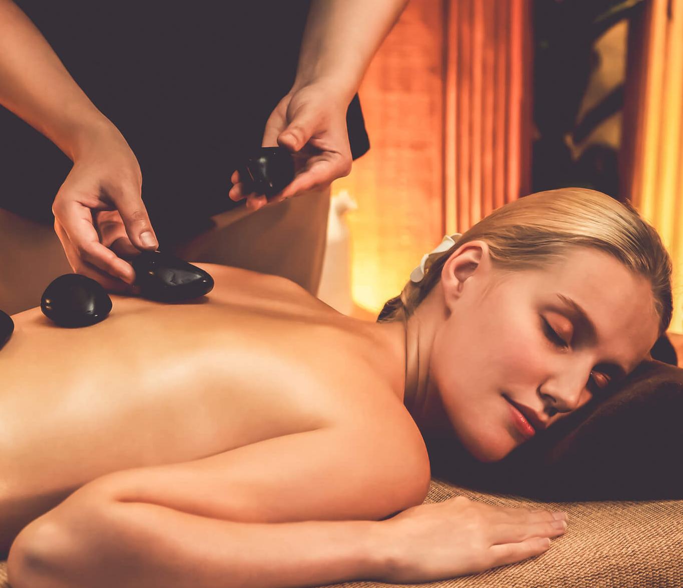 Massage therapist performing hot stone massage on a woman at Navi Spa